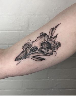 Experience the magic with a unique tattoo featuring a bird, flower, and skull in intricate dotwork style by Claudia Smith.