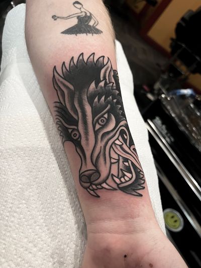 Get inked with a fierce and timeless wolf design by renowned artist Barney Coles. Traditional style meets nature's beauty in this stunning tattoo.