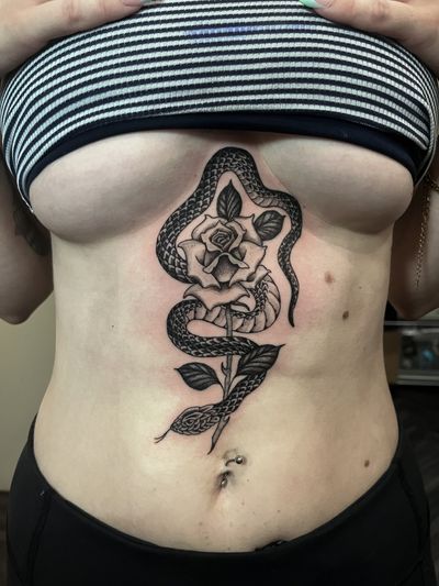 Get inked with a stunning illustrative tattoo featuring a snake entwined around a vibrant rose, expertly done by Barney Coles.