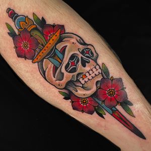 Impressive neo-traditional tattoo by Jethro Wood featuring a striking combination of flower, skull, and dagger motifs.