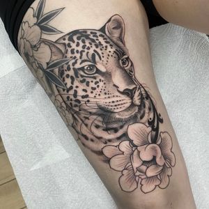 Elegant black and gray tattoo combining a fierce jaguar with a delicate flower, expertly done by the talented artist Sam Waiting.