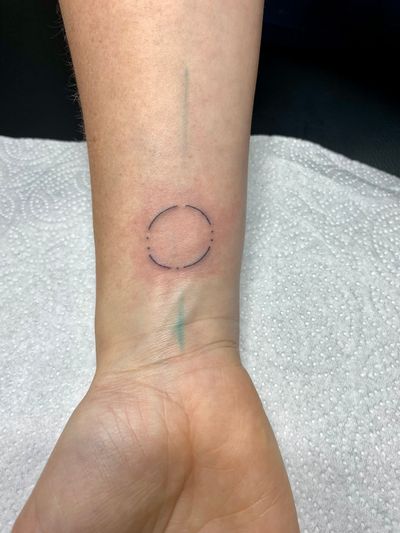 A beautifully crafted fine line and illustrative tattoo of a circle, meticulously hand poked by the talented artist Charlotte Pokes.