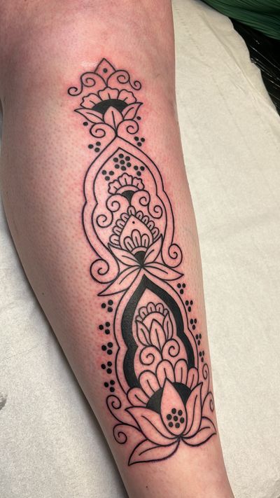 Exquisite ornamental tattoo featuring a lotus flower, intricate patterns, and a mandala design by Claudia Vicente.