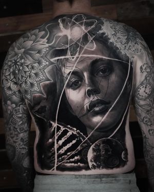 Experience the beauty of the universe with this stunning tattoo by Milan Boros, featuring a blend of planets, atoms, DNA, and a woman in mesmerizing detail.