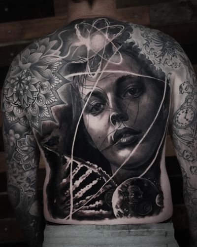 Experience the beauty of the universe with this stunning tattoo by Milan Boros, featuring a blend of planets, atoms, DNA, and a woman in mesmerizing detail.