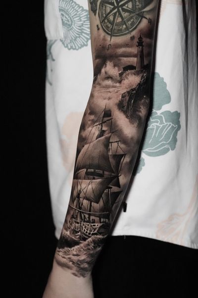 Experience the beauty of the sea with this black and gray realism tattoo featuring a lighthouse and ship, created by Milan Boros.