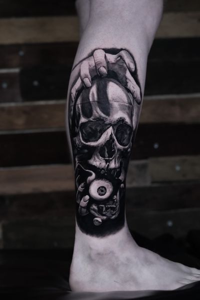 Detailed black and gray tattoo by Milan Boros featuring a chilling skull with haunting eyes and hands.