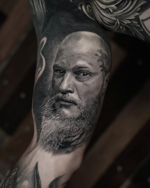 Capture the fierce spirit of Ragnar in this stunning black and gray realism tattoo by renowned artist Milan Boros.