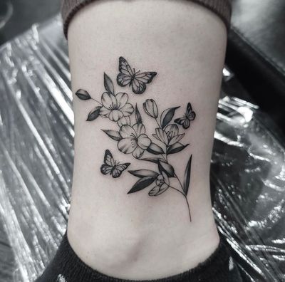 Featuring a beautiful butterfly intertwined with a delicate flower, this tattoo by Tom Boxell showcases stunning floral and illustrative elements.