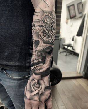 Intricate black and gray illustrative tattoo of a skull with a watch and clock elements by artist Tom Boxell. Timeless and mysterious design.