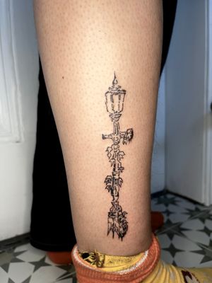 Get a unique illustrative tattoo of a street lamp and post done in fine line style by the talented artist Emily Bonnet.
