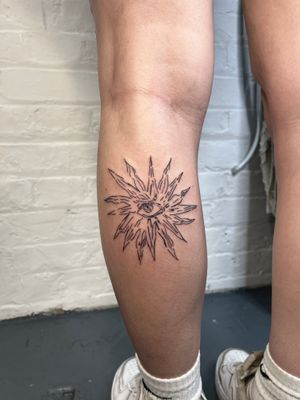 Discover the intricate beauty of this fine line illustrative tattoo featuring a stunning sun and eye motif by talented artist Emily Bonnet.