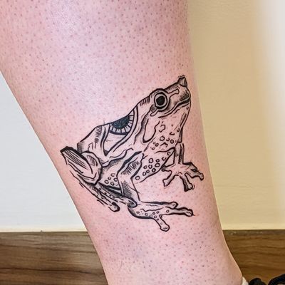 Get mesmerized by this unique and mesmerizing tattoo by Adam McDade, featuring a frog and evil eye motif in an illustrative style.