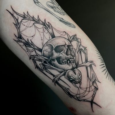 Get a unique and edgy illustrative tattoo featuring a spider and skull design, skillfully done by the talented artist Kat Jennings.