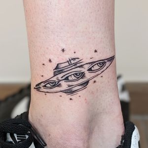 Unique illustrative tattoo featuring a UFO and eye motif, designed by talented artist Adam McDade.