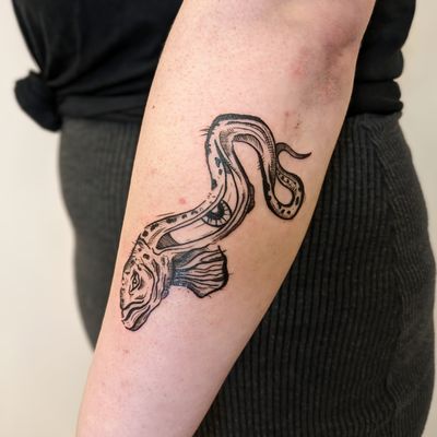 Get a unique and eye-catching tattoo by artist Adam McDade, featuring a fish motif in illustrative style with etch and woodcut details.