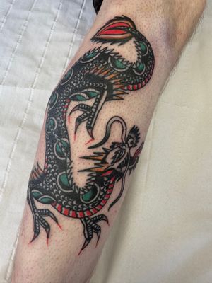 Experience the raw power and mystique of a traditional dragon tattoo expertly crafted by Jakob Isaac. Embrace the ancient symbolism and fierce beauty of this timeless design.