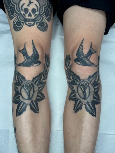 Get a timeless and classic traditional tattoo featuring a beautiful swallow and rose motif, expertly done by renowned artist Jakob Isaac.