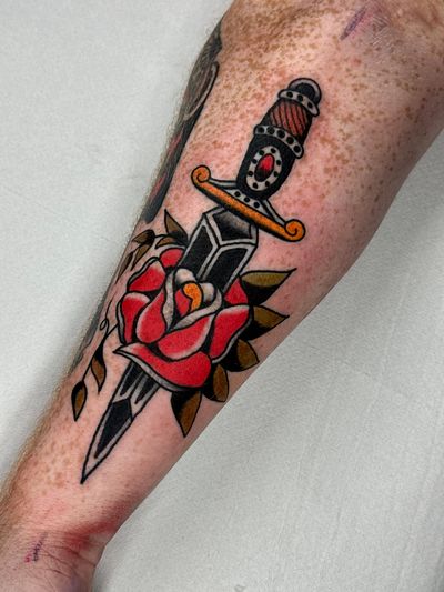 Classic traditional tattoo design featuring a bold rose and dagger motif by Jakob Isaac.