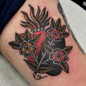 Get inked with a stunning traditional tattoo of a flower and sacred heart by Jakob Isaac, a master in the art of body ink.