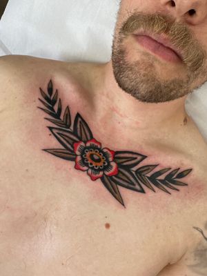 Get inked with a timeless traditional tattoo featuring a beautiful rose and delicate branch design by the talented artist Jakob Isaac.