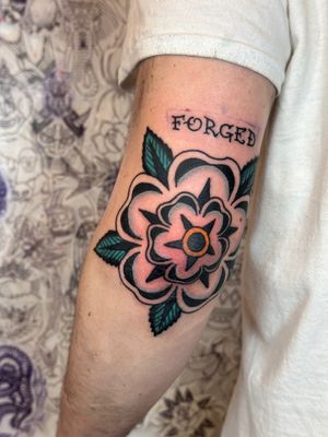 Get inked with a striking traditional tattoo featuring a beautiful tudor rose flower design by Jakob Isaac. Timeless and elegant!