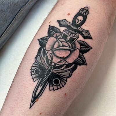 Get inked with this classic design by Jakob Isaac, featuring a bold rose entwined with a sharp dagger in traditional style.