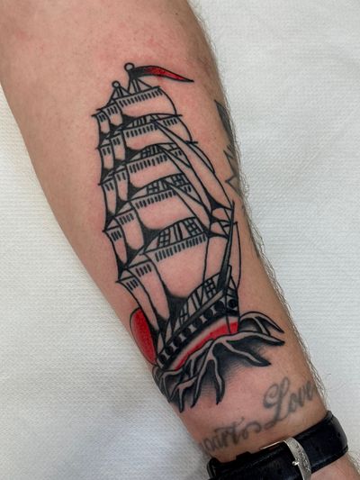 Sail away with this classic traditional ship tattoo by the talented artist Jakob Isaac. Perfect for those with a love for the sea and adventure.