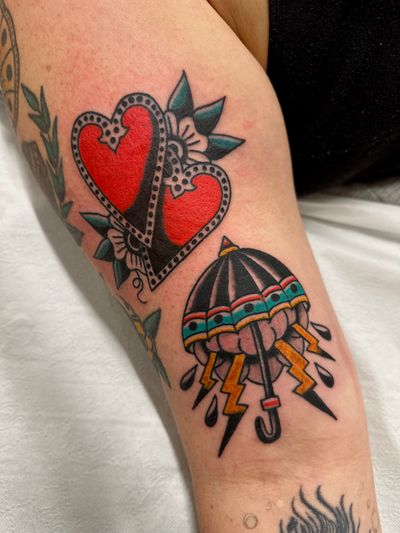Get a classic tattoo featuring a heart and umbrella motif by the talented Jakob Isaac.