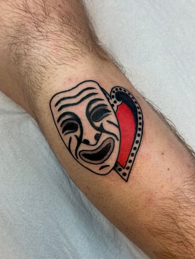 Add drama to your skin with this traditional tattoo featuring a heart, theatric elements, and a mask by the talented artist Jakob Isaac.