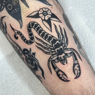 Get inked with a fierce scorpion design by Jakob Isaac, expert in traditional style tattoos. Embrace your inner strength with this striking piece.