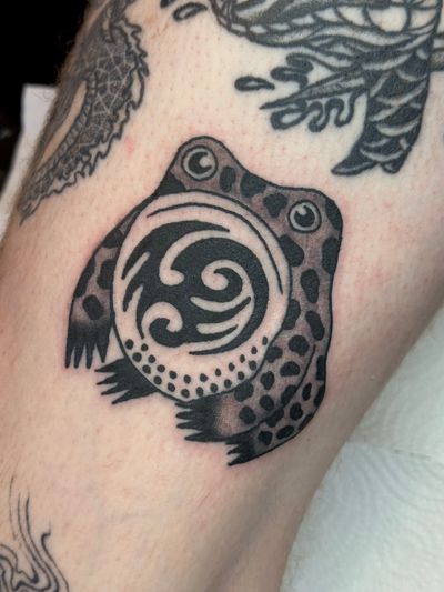 Get a unique frog tattoo by Jakob Isaac, blending illustrative and traditional styles for a timeless piece of body art.