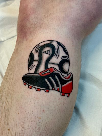 Capture the essence of the game with this traditional tattoo featuring football boots and ball. Expertly done by Jakob Isaac.