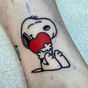 Get a whimsical illustrative tattoo of Snoopy surrounded by a heart, created by the talented artist Jakob Isaac.