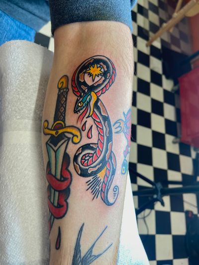 Get inked with this classic traditional tattoo design featuring a snake and dagger by the talented artist Flashbyaj. Perfect for those who love bold and timeless ink!