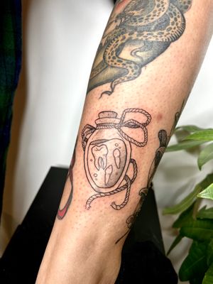 Unique dotwork tattoo featuring a bottle intertwined with teeth, expertly crafted by talented artist Michelle Harrison.