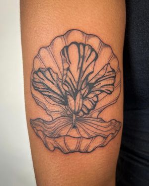 Beautifully detailed illustrative tattoo featuring a delicate orchid and seashell design done by the talented artist Jack Howard.