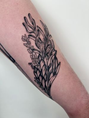 Illustrative tattoo by Jack Howard featuring a bundle of herbs and botanical branches, a natural and artistic design.