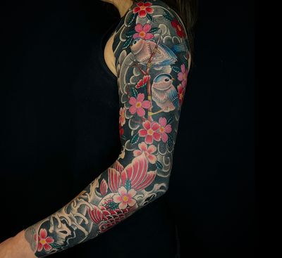 Beautiful Japanese tattoo featuring a sparrow, koi fish, and cherry blossom by artist Carlos Zucato. A harmonious blend of nature and tradition.