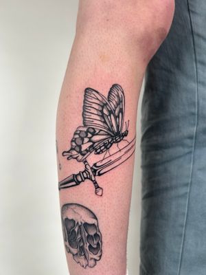 A stunning illustrative tattoo combining a delicate butterfly with a sharp knife, expertly crafted by artist Jack Howard.