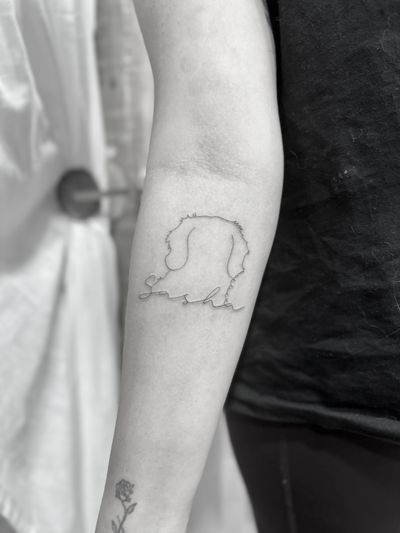 Perfectly executed fine line and small lettering tattoo of a dog outline by tattoo artist Aleks Fanta.