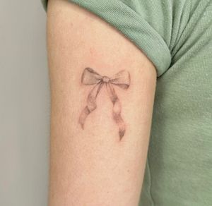 Unique dotwork hand-poked bow tattoo designed by artist Alina Wiltshire for a timeless and intricate look.