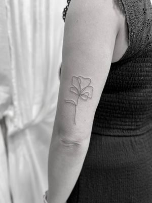 Exquisite fine line tattoo of a delicate flower, expertly done by Aleks Fanta
