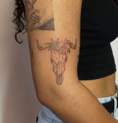Get a unique hand-poked micro-realism tattoo of a cow skull with intricate dotwork details by talented artist Alina Wiltshire.