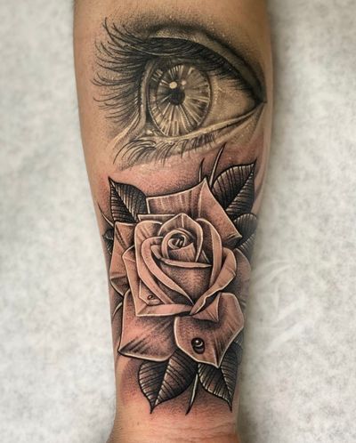 Black and gray tattoo featuring a detailed rose with whip shading and a mesmerizing eye, by artist Justin JP Param.