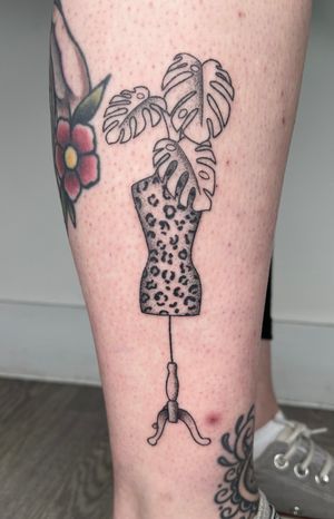 Unique hand-poked tattoo by Marketa featuring a stylish mannequin and monstera leaf design done in dotwork style.