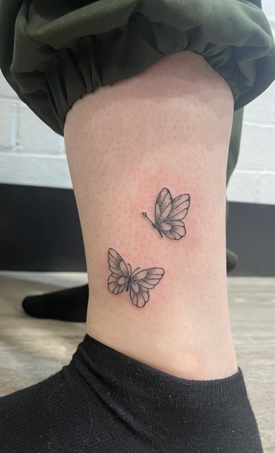 Elegant hand-poked butterfly tattoo in dotwork style, created by the talented artist Marketa.