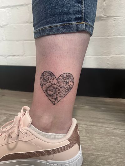 Unique and delicate hand-poked tattoo by Marketa combining dotwork and fine lines to create a stunning heart and flower motif.