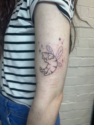 Fine line illustrative tattoo of a graceful cat with fairy wings, done by Marketa.handpoke. Elegant and whimsical design.