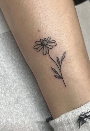 Experience the beauty of hand-poked dotwork with this exquisite daisy tattoo by Marketa. A timeless symbol of purity and innocence.